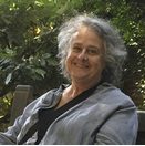 A woman sitting on top of a wooden bench.